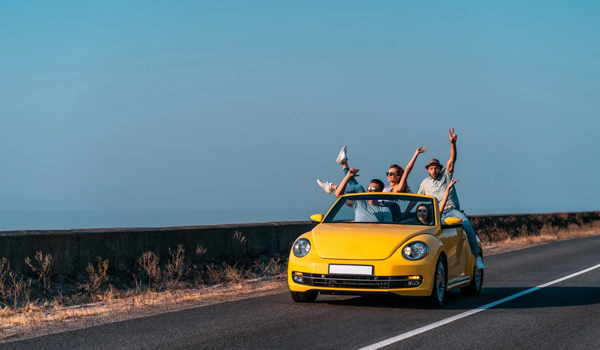 Menschen auf der Straße genießen die Fahrt in einem gelben Auto.